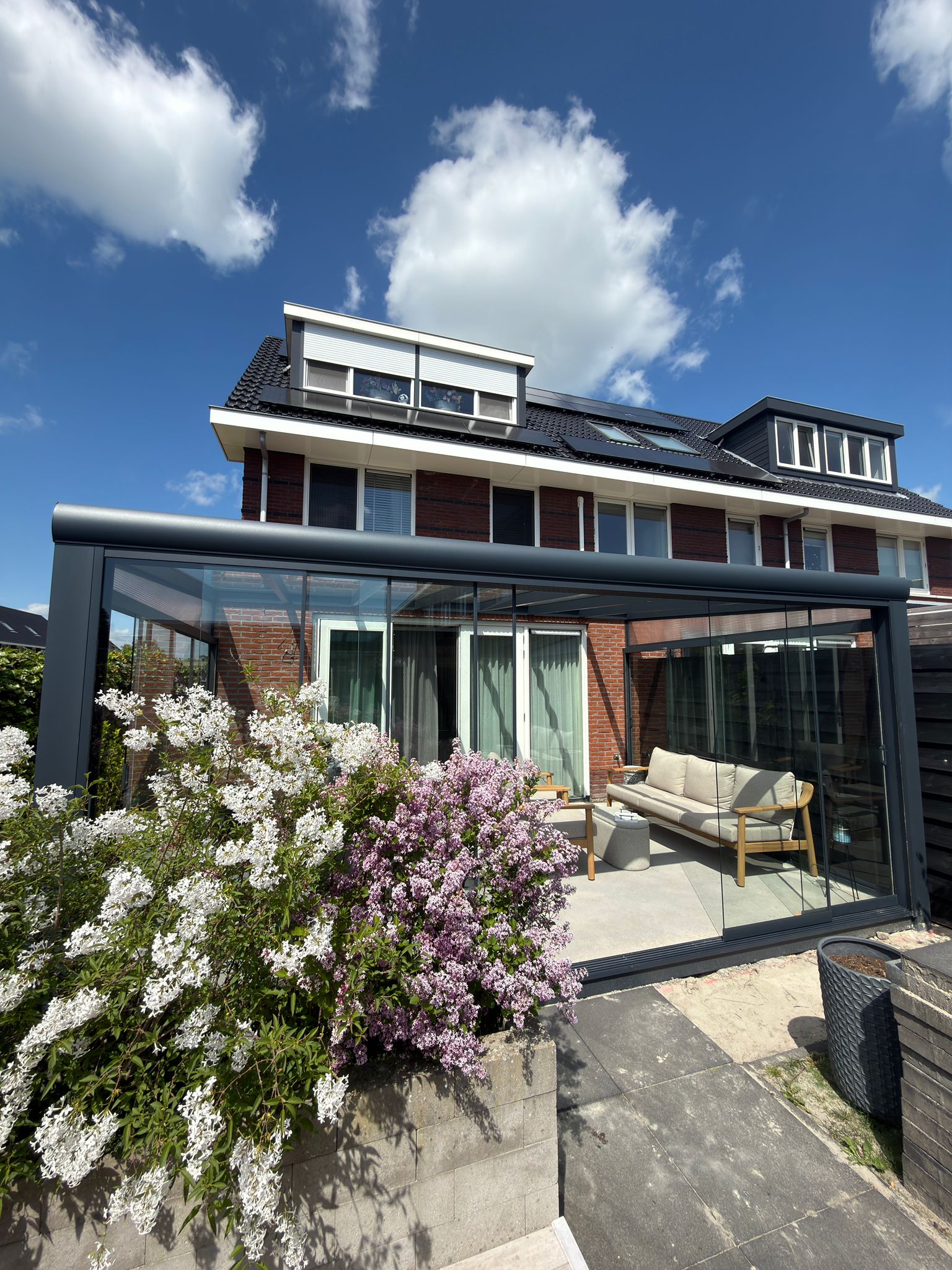 Volledig gesloten aluminium veranda met glazen schuifwanden aan achtergevel van rijtjeswoning
