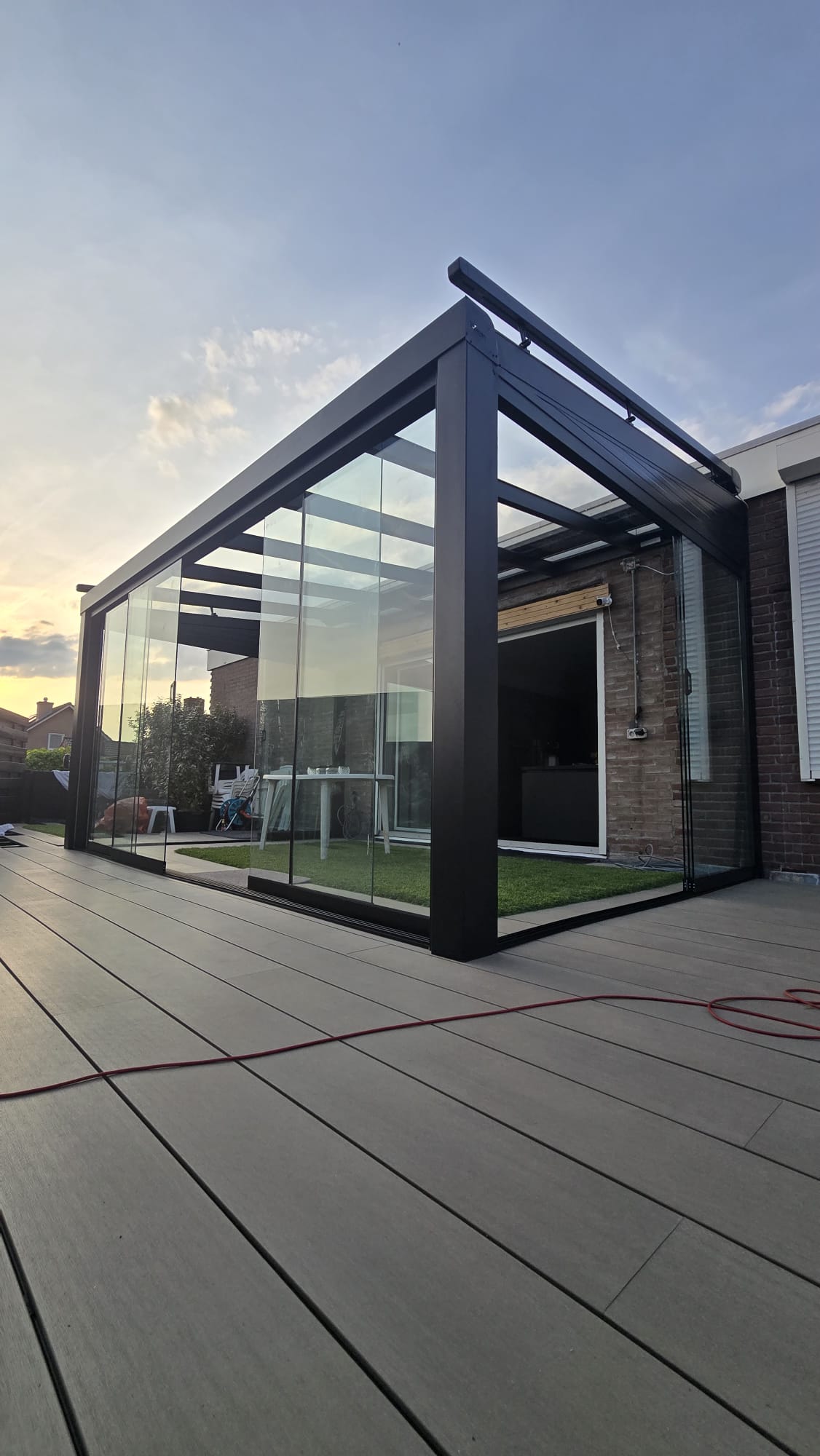 Aluminium veranda met polycarbonaat dak en zijwand geplaatst aan achtergevel van woning