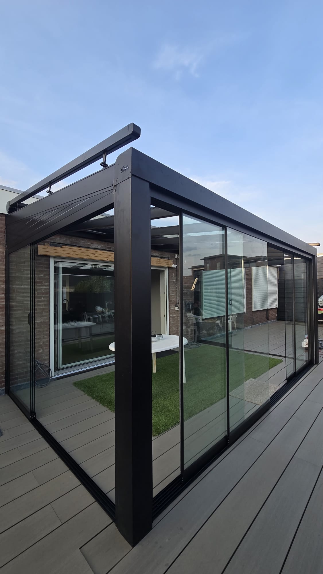 Moderne aluminium veranda met glazen schuifwanden en dichte zijwand aan achtergevel van woning