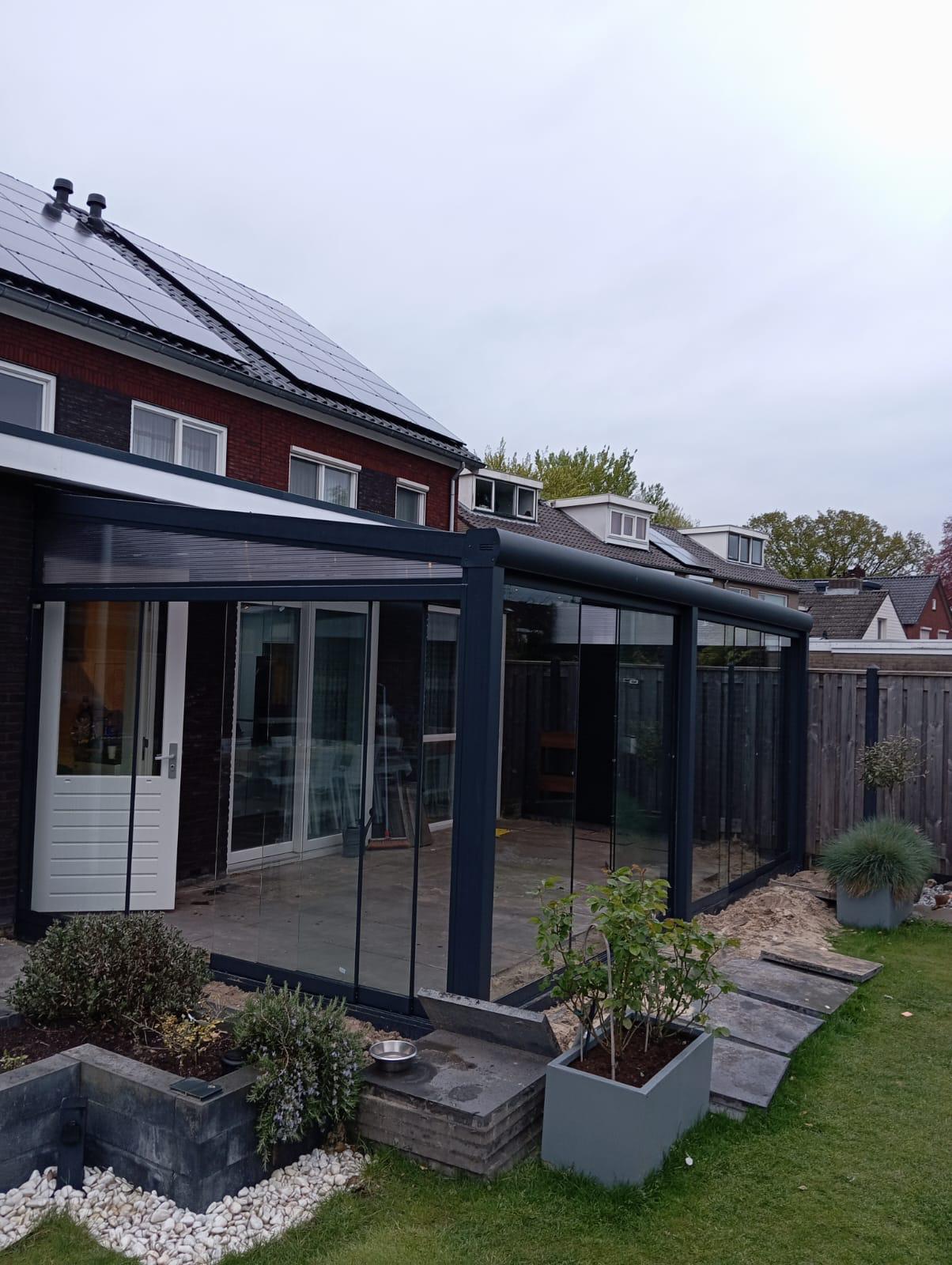 Moderne aluminium veranda met volledig glazen schuifwanden aan achtergevel van woning